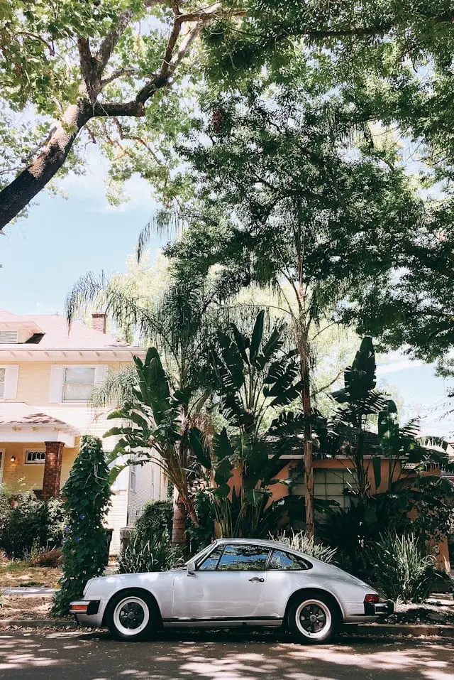 Porsche 930 garrée devant une grande maison avec un jardin
