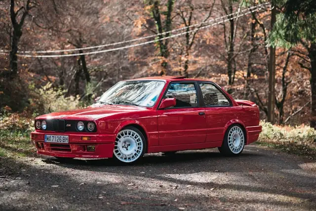 BMW M3 E30 rouge dans une forêt