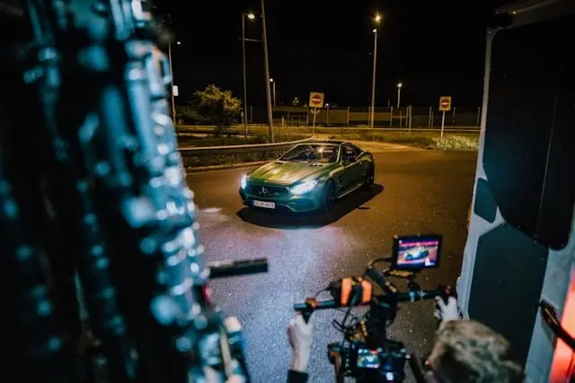 Caméraman qui filme une Mercedes AMG verte de nuit sur route ouverte