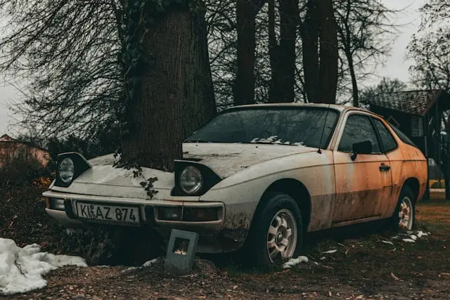 Porsche 944 rouillée et abandonnée dans un tronc d'arbre