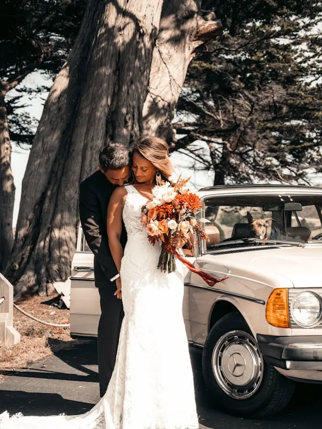 Mariés avec un bouquet à côté d'une Mercedes W123