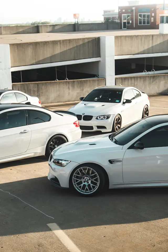Plusieurs BMW E90 coupé blanches garées en haut d'un parking