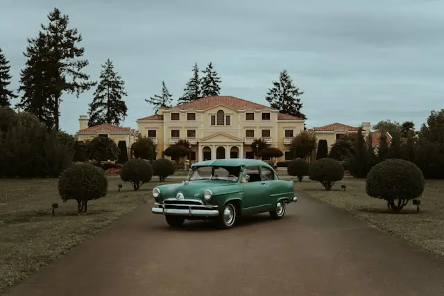 Vieille voiture americaine verte devant une maison
