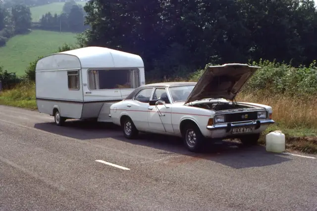 Voiture ancienne anglaise avec caravane en panne