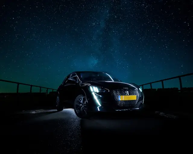 Peugeot 208 noire de nuit avec un ciel étoilé